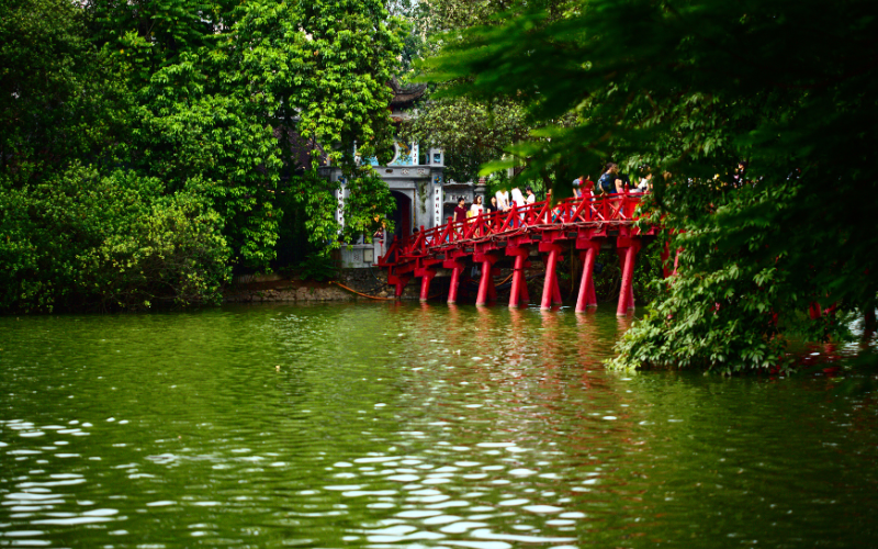 Le pont The Huc, avec sa couleur rouge distinctive, se démarque au milieu du lac Hoan Kiem en reliant le temple Ngoc Son