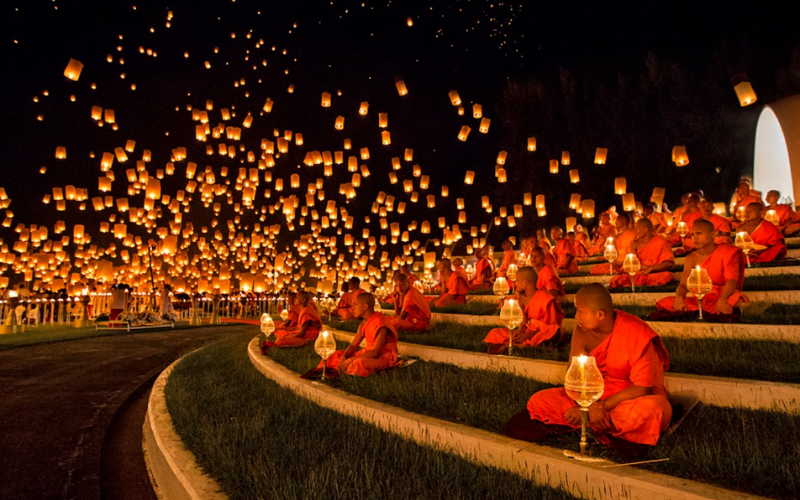 Moine bouddhiste allumant une lanterne lors du festival Yi Peng en Thaïlande