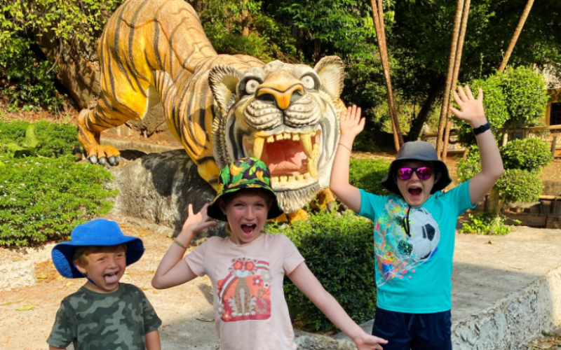 Les enfants posent joyeusement devant la statue du tigre au temple.